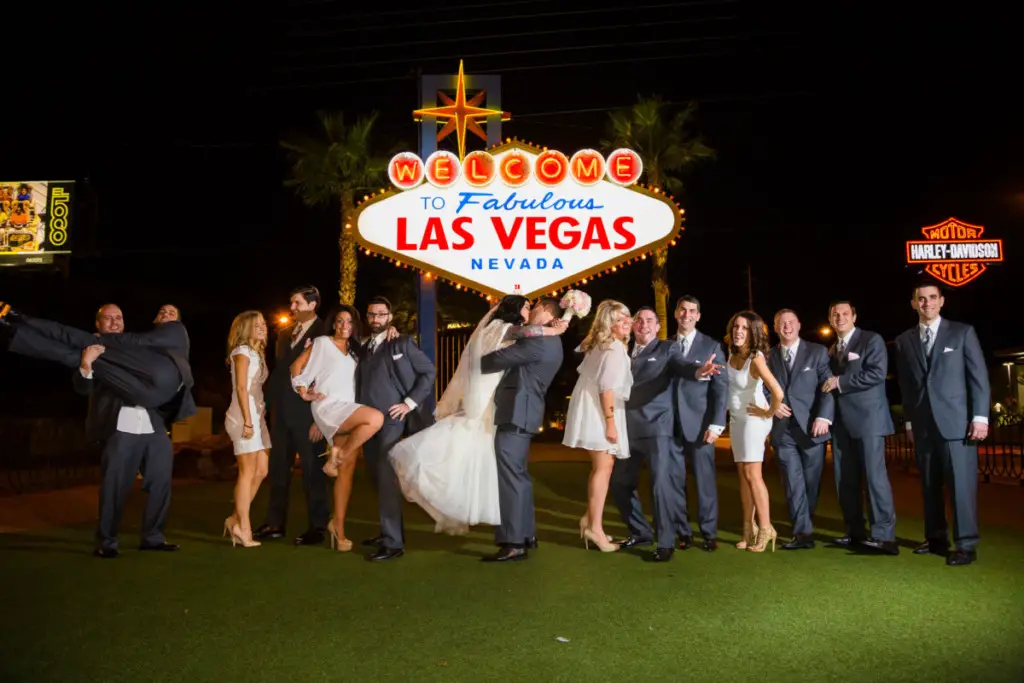 wedding party in front of welcome to las vegas sign