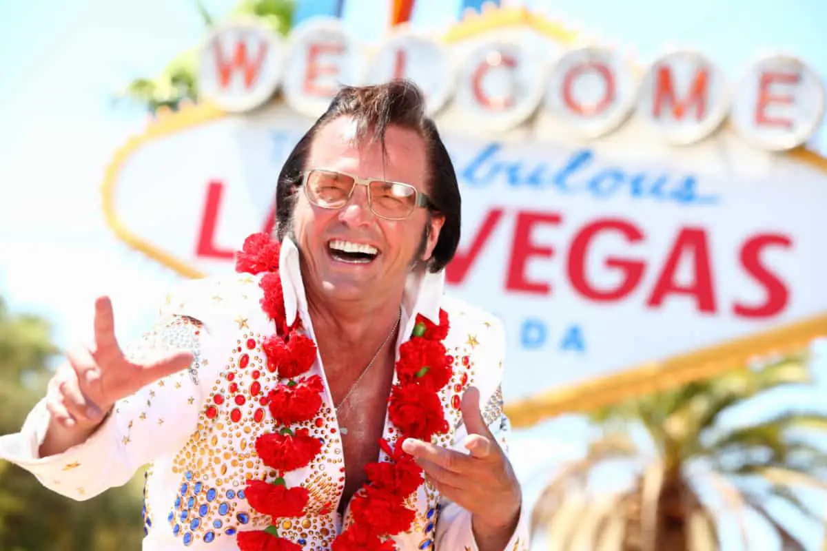 Elvis impersonator in front of welcome to las vegas sign