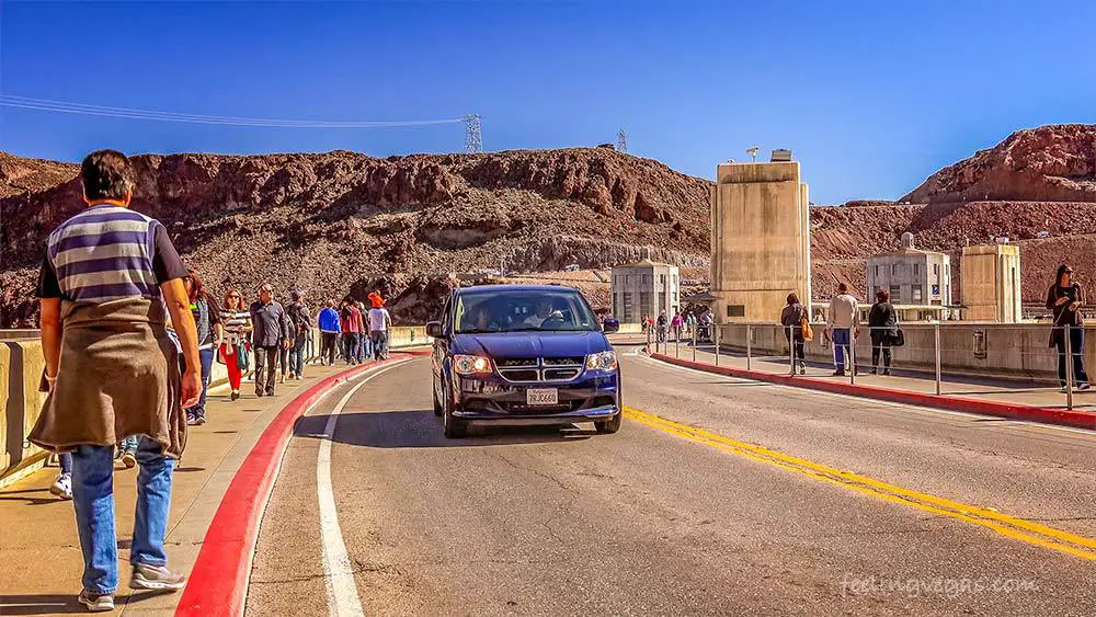 Visitors walk and drive across the Hoover Dam