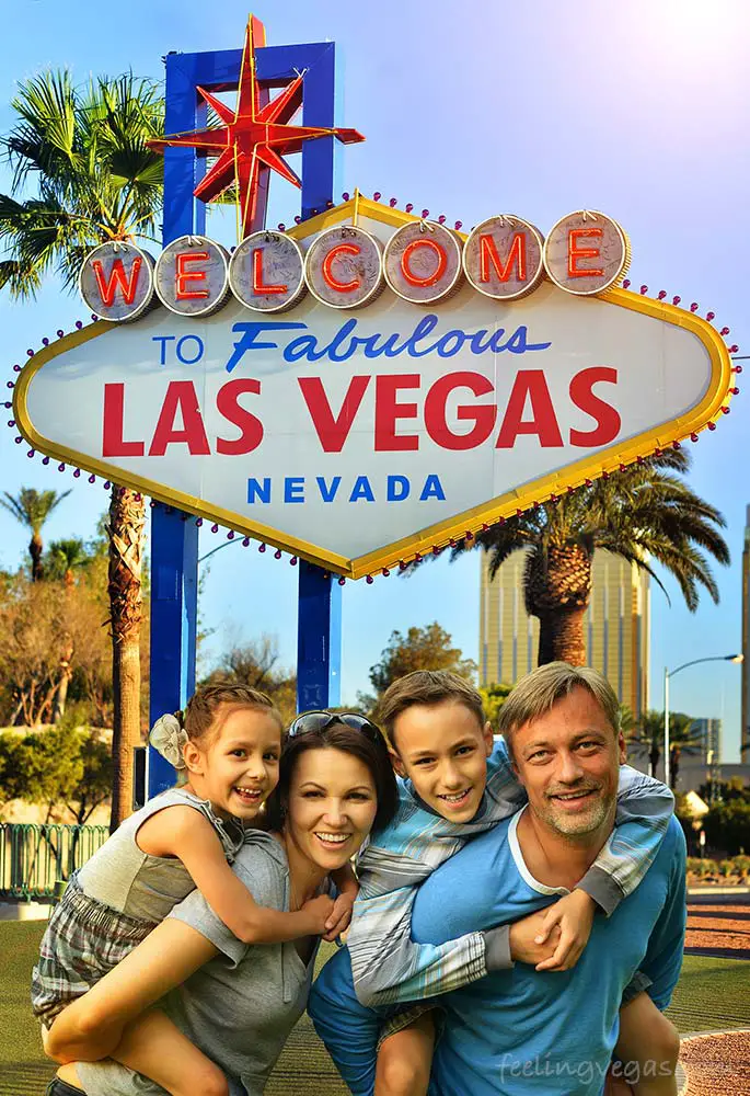 14 Family-Friendly Hotels in Las Vegas (Off The Strip) 2 Family with kids in front of Las Vegas sign.
