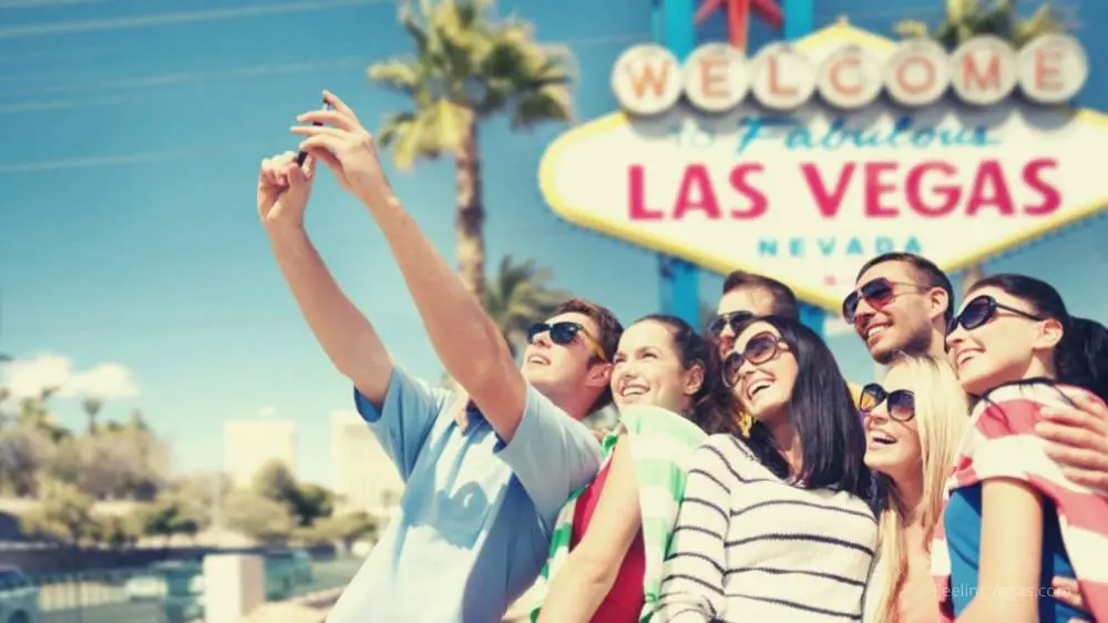 Casually dressed people in front of the Las Vegas sign.