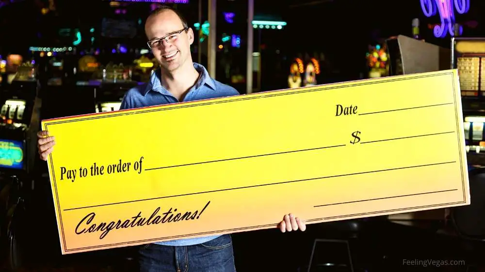 man in a casino with a big winning cheque