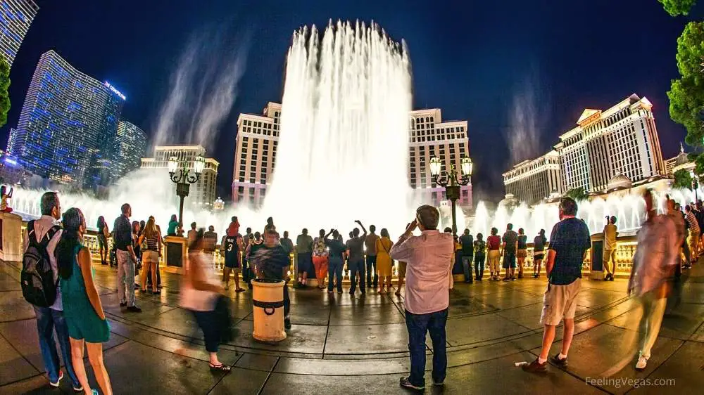 Visitors walk around the Bellagio Fountains at night on the Las Vegas Strip