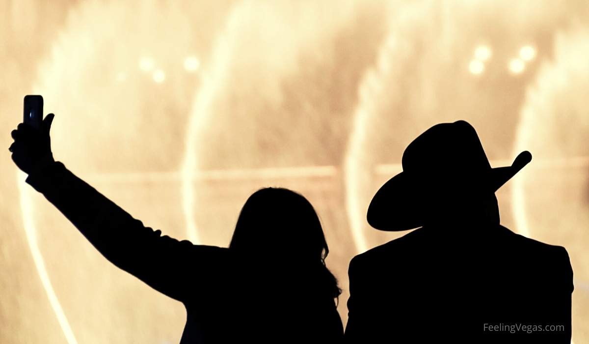 A Las Vegas visitor wearing a cowboy hat in front of the Bellagio Fountains.