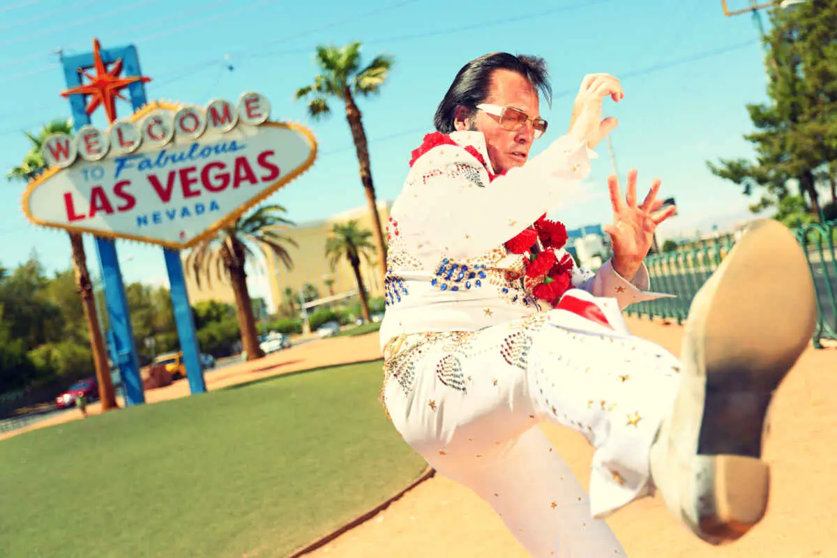 All Shook Up Vegas: A Must See Elvis Tribute Experience 3 Elvis impersonator in front of the Welcome to Fabulous Las Vegas sign